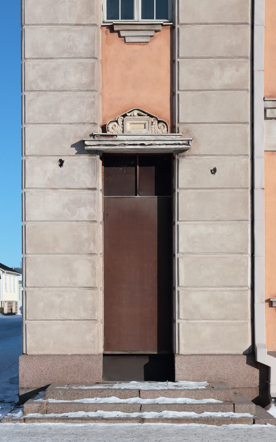 A tall doorway closed off with a single sheet of board fitted inside the frame.